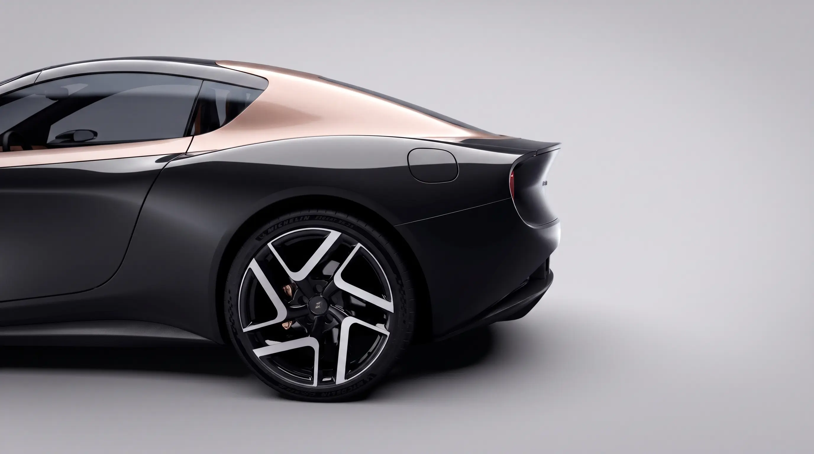 Roadster rear quarter and wheel, bronze roof over black bodywork, on a pale studio backdrop